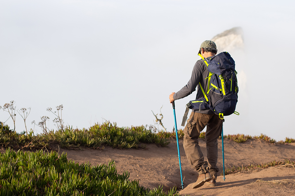 Man trekking on a scenic hilltop under a clear blue sky